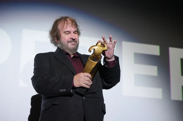 Peter Jackson, barbu et vêtu d'une veste sombre sur une chemise bordeaux, tenant une statuette dorée sur la scène du Festival du film de Sitges.