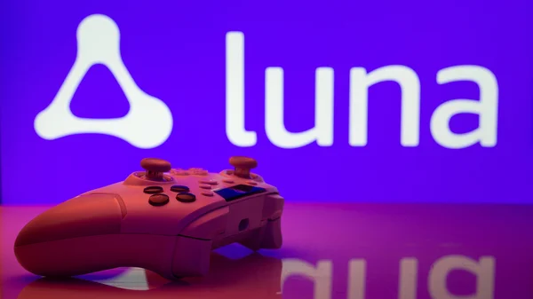 Une manette de jeu rouge posée sur une surface réfléchissante devant un écran violet affichant le logo Amazon Luna, illustration du service de cloud gaming.
