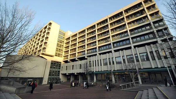 Bâtiments brutalistes en béton du complexe judiciaire de Munich, abritant le tribunal d'instance, les tribunaux régionaux I et II, le tribunal régional supérieur et le parquet, avec des piétons traversant une esplanade dallée.
