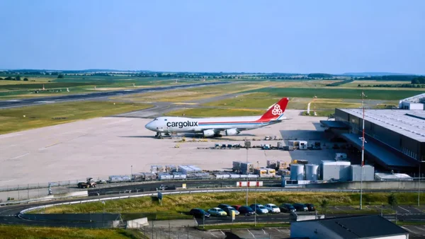 Un avion-cargo Cargolux stationné sur le tarmac de l’aéroport de Vatry, devant un entrepôt logistique, avec les pistes et les champs de la Marne en arrière-plan
