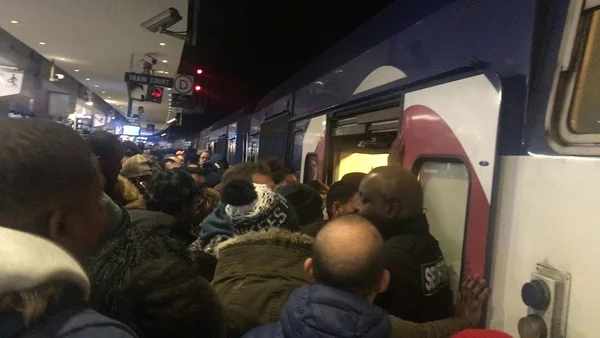À la gare du Nord à Paris, une foule dense de voyageurs en vêtements d'hiver se presse vers les portes ouvertes d'une rame de RER D bondée à l'heure de pointe.