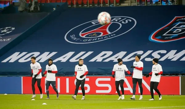 Les joueurs du PSG et d'Istanbul Basaksehir, portant des t-shirts "No to Racism", posent un genou à terre avant le coup d'envoi d'un match de Ligue des champions.