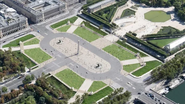 Vue aérienne de la place de la Concorde à Paris avec l'obélisque de Louxor au centre, les fontaines, les pelouses et les immeubles haussmanniens alentour, la Seine et des bateaux à droite