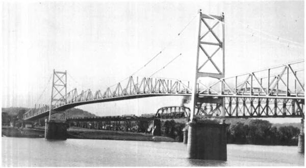 Pont en acier du Silver Bridge traversé par un train à vapeur, photographié en noir et blanc avant son effondrement en 1967 à Point Pleasant, dans le comté de Mason.