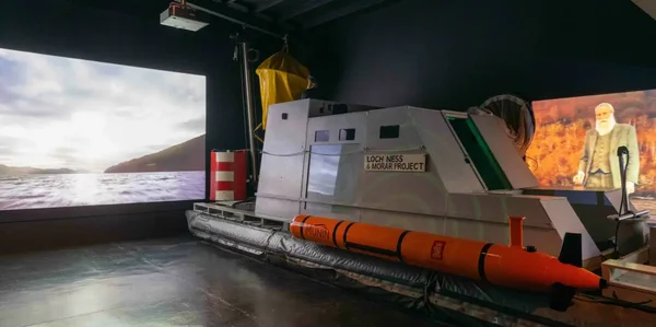Exposition intérieure présentant un modèle de bateau nommé 'LOCH NESS & MORAR PROJECT' et un véhicule sous-marin autonome orange appelé 'MUNIN'